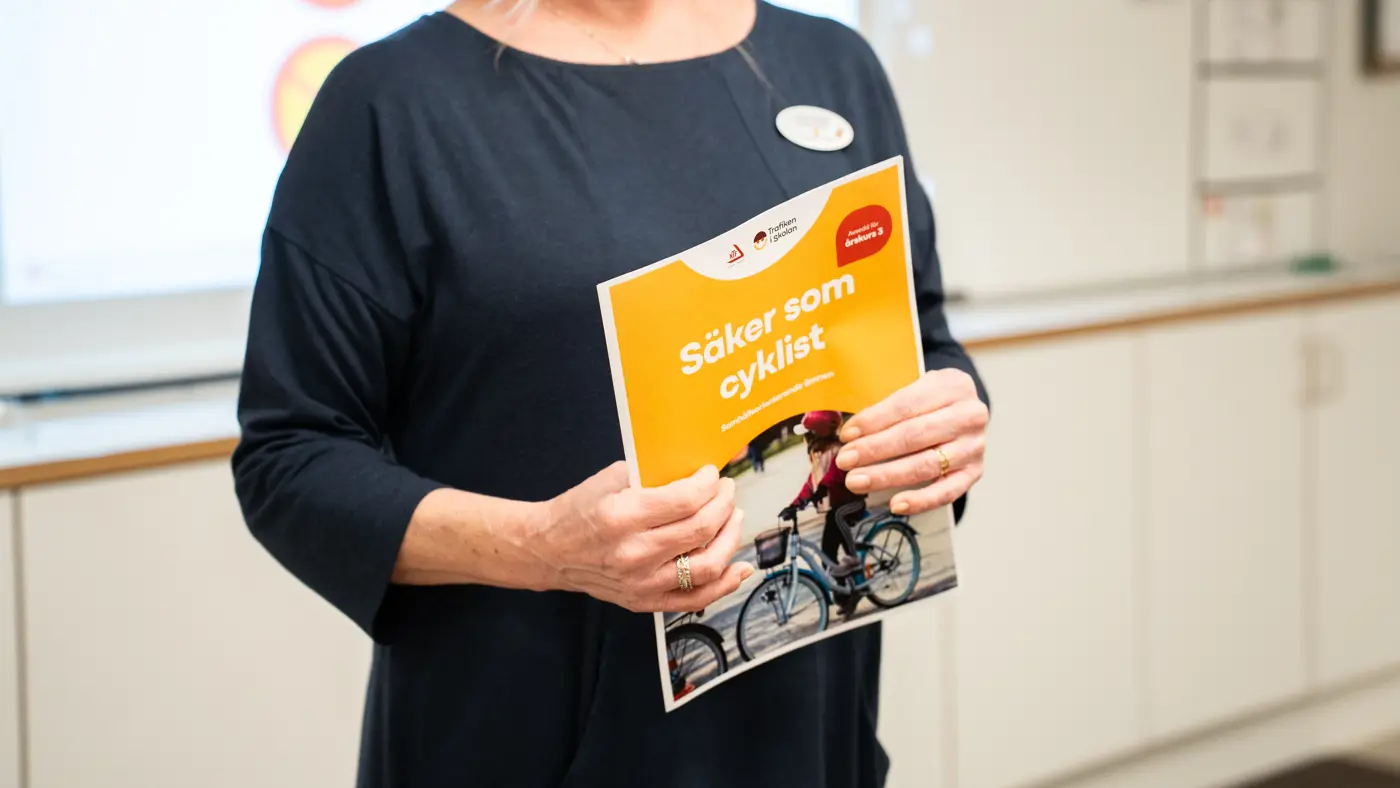 Närbild på en person som håller i lektionsförslaget "Säker som cyklist" för årskurs 3.