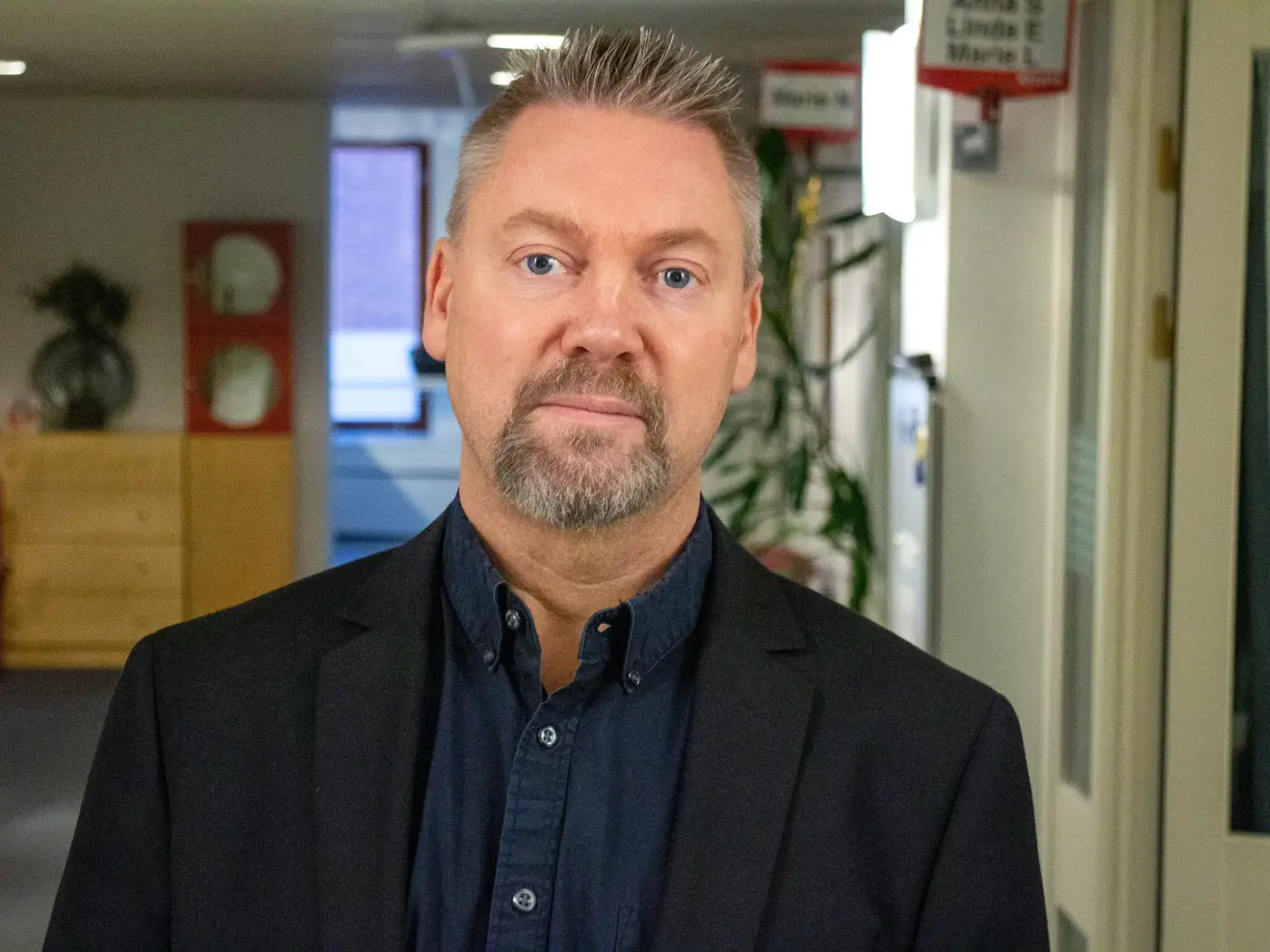 Porträttbild på en man med blå skjorta och svart kavaj.