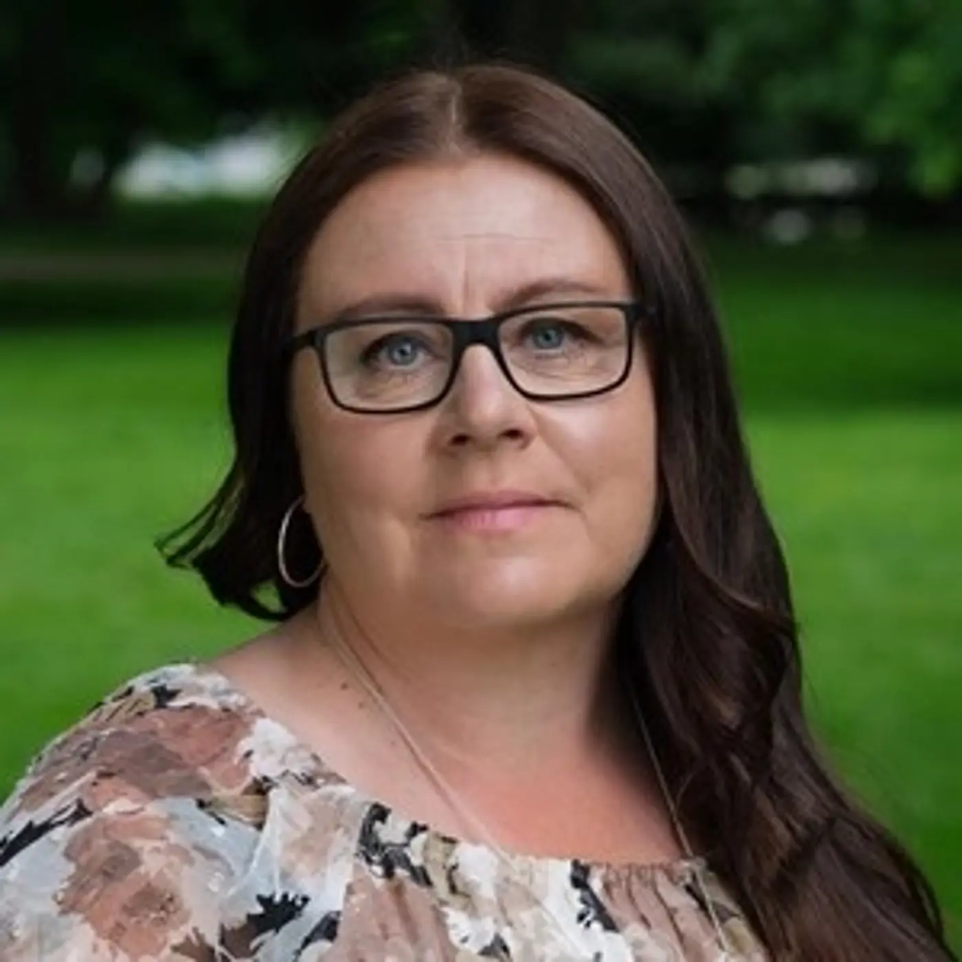 En porträttbild på en kvinna med långt mörkbrunt hår och glasögon.