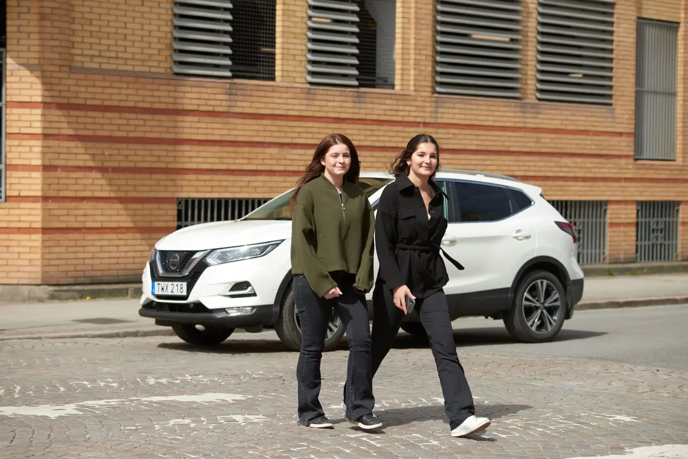 Två ungdomar går över ett obevakat övergångsställe. Framför övergångsstället väntar en bil.