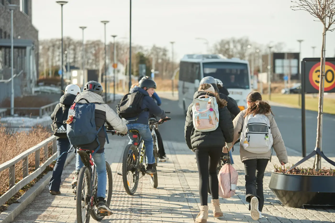 En grupp skolbarn cyklar och promenerar tillsammans.