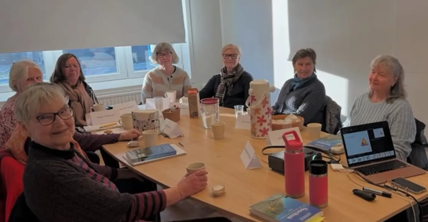 En grupp människor sitter runt ett konferensbord.