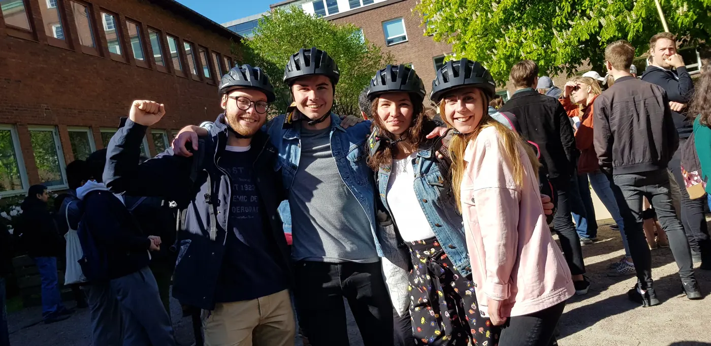 Fyra unga vuxna står framför kameran med varsin hjälm på huvudet.