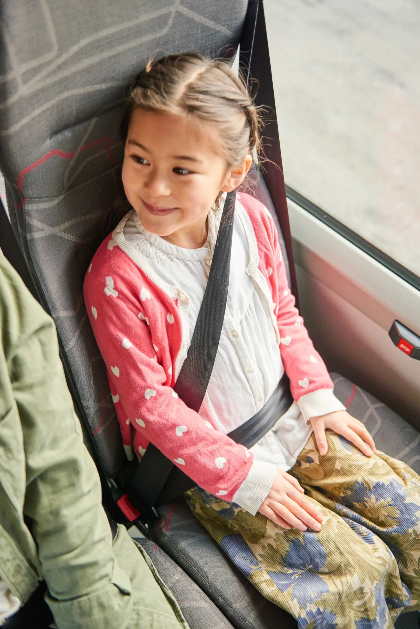 Ett barn sitter vid fönsterplatsen i en buss, med bältet fastspänt.