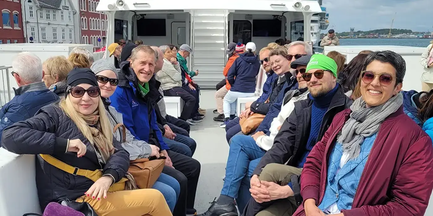 Ett tiotal personer sitter på en båt och tittar leende in i kameran.