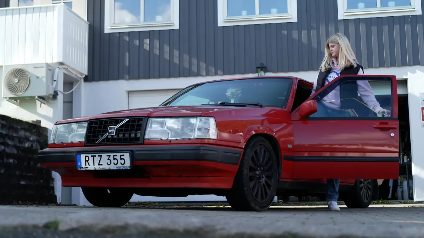 En ung tjej som är påväg att sätta sig i sin röda A-traktor