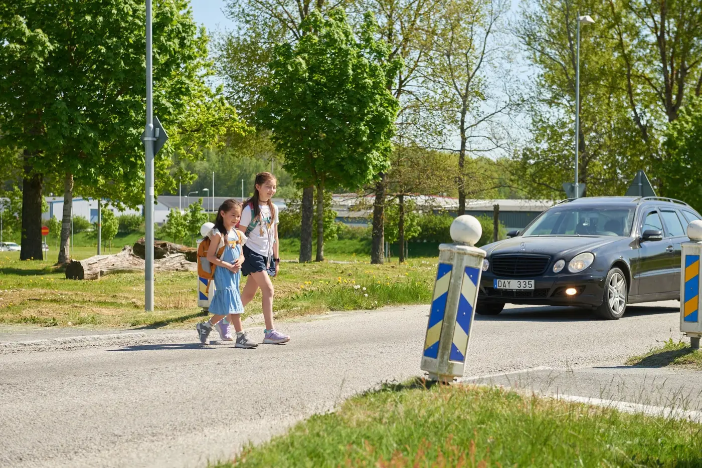 En bil väntar in två barn som passerar ett övergångsställe.