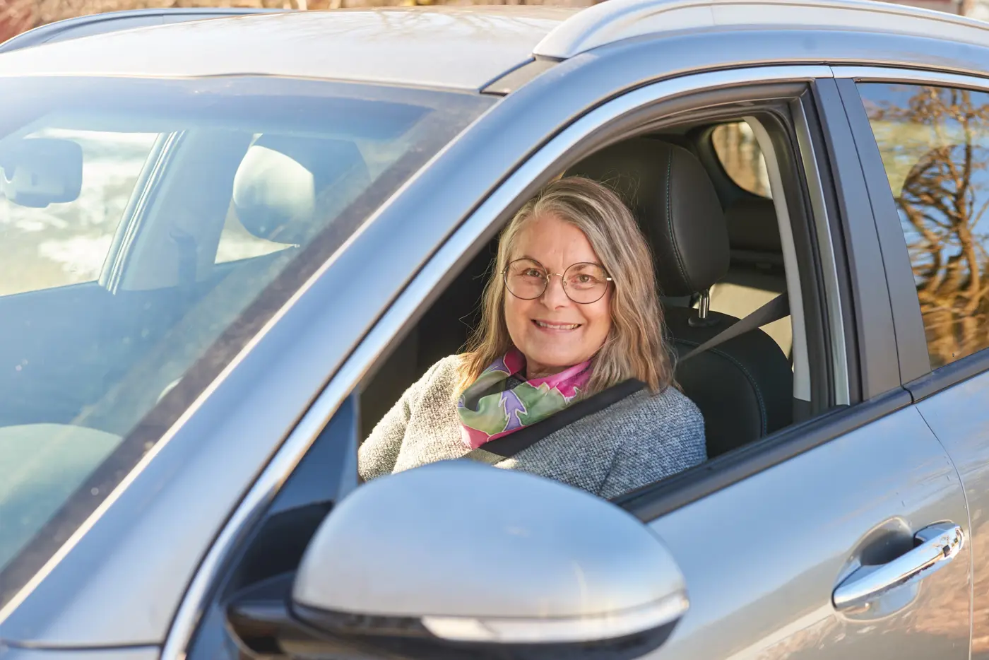 En äldre kvinna kör bil.