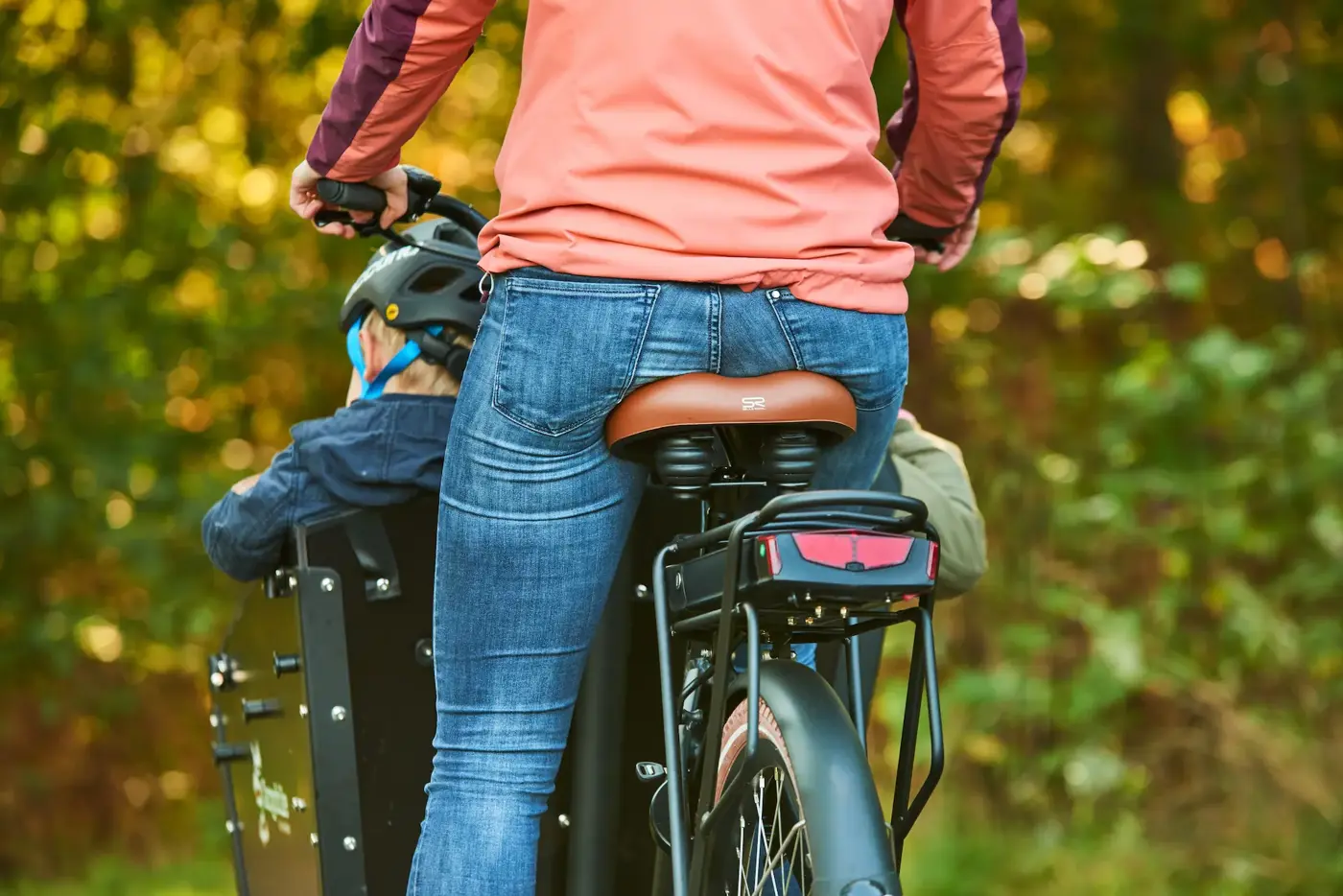 En mamma som skjutsar sina barn på lådcykel.