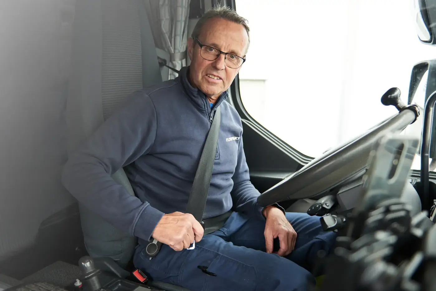 En lastbilsförare knäpper sitt bilbälte.