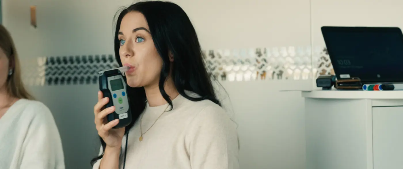 En ung kvinna blåser i en alkomätare.