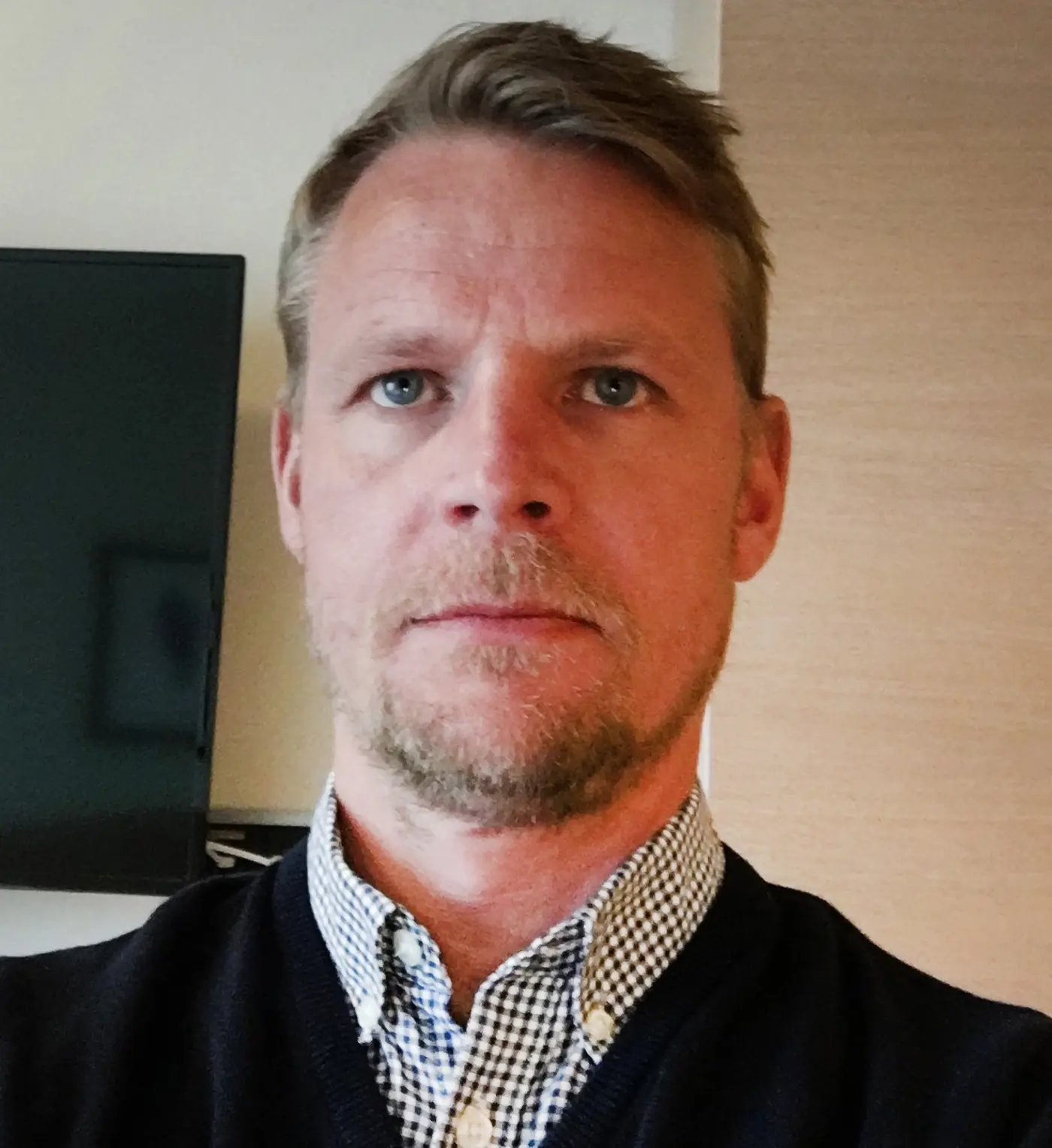 Porträttbild på en man med rutig skjorta.