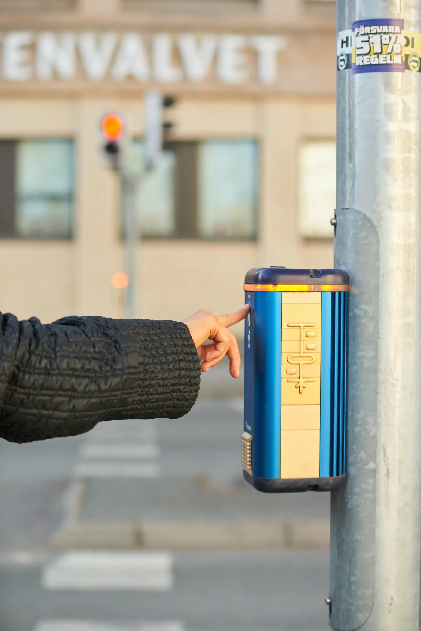 Närbild på en hand som trycker på knappen vid ett övergångsställe