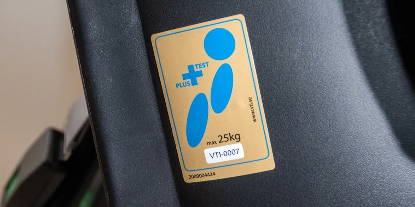 En klisterlapp på en bilbarnstol med texten "plustestet".