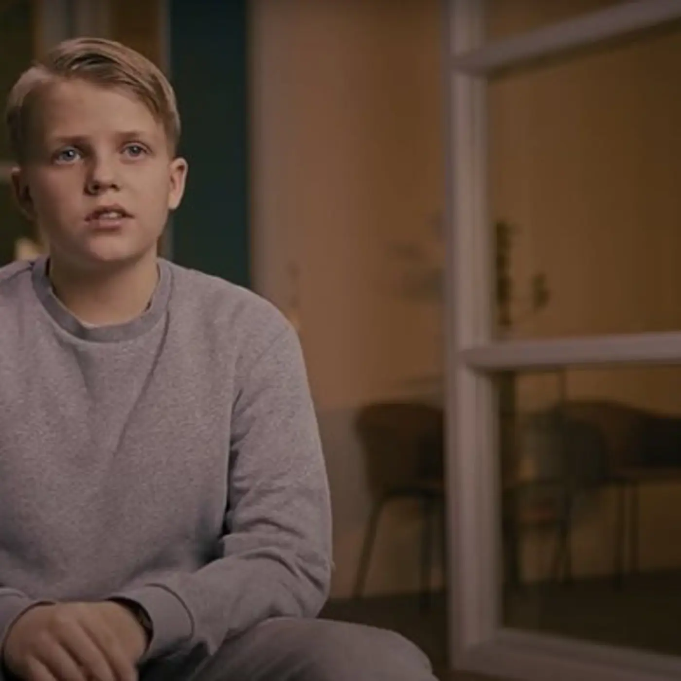 En pojke i 14-årsåldern sitter på en stol och bli intervjuad.