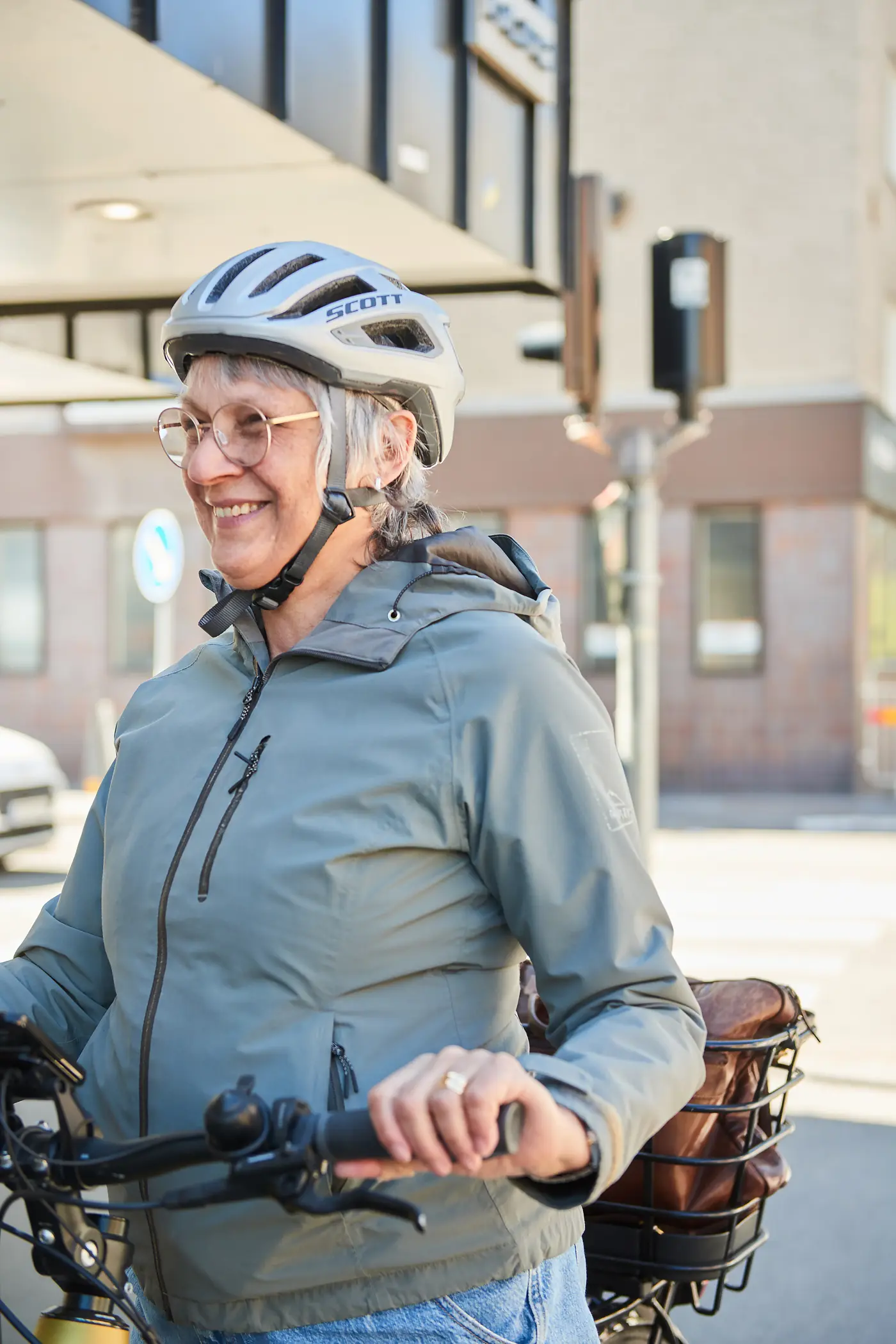 En leende äldre kvinna på cykel med cykelhjälm.