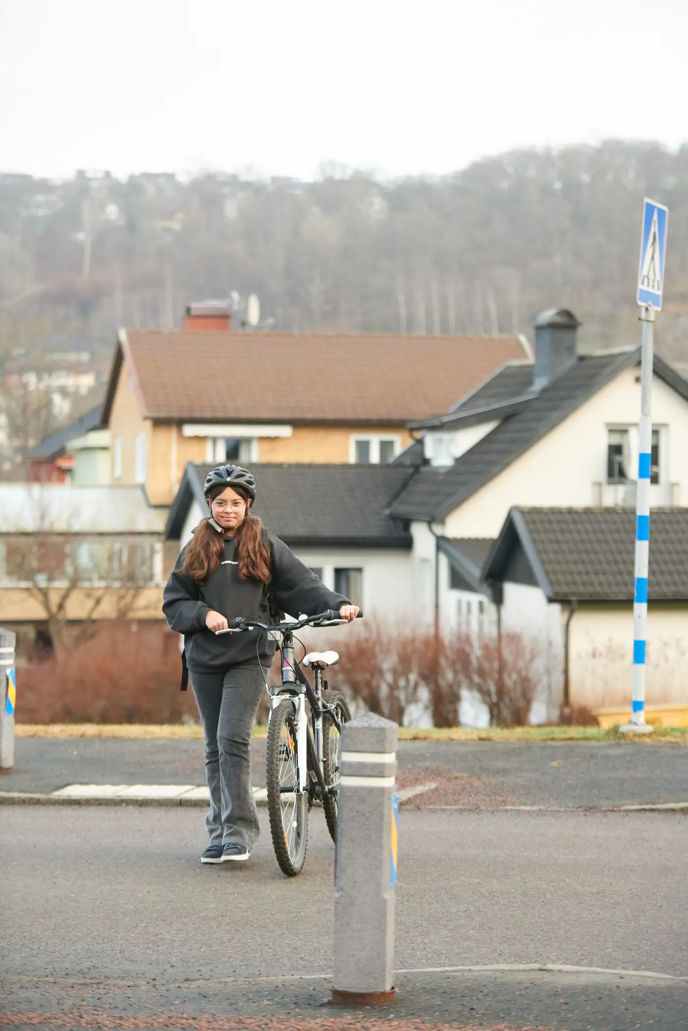 Ett skolbarn står med en cykel och väntar på att gå över vägen