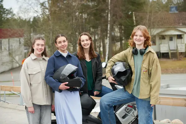 grupp med ungdomar som står vid en moped 