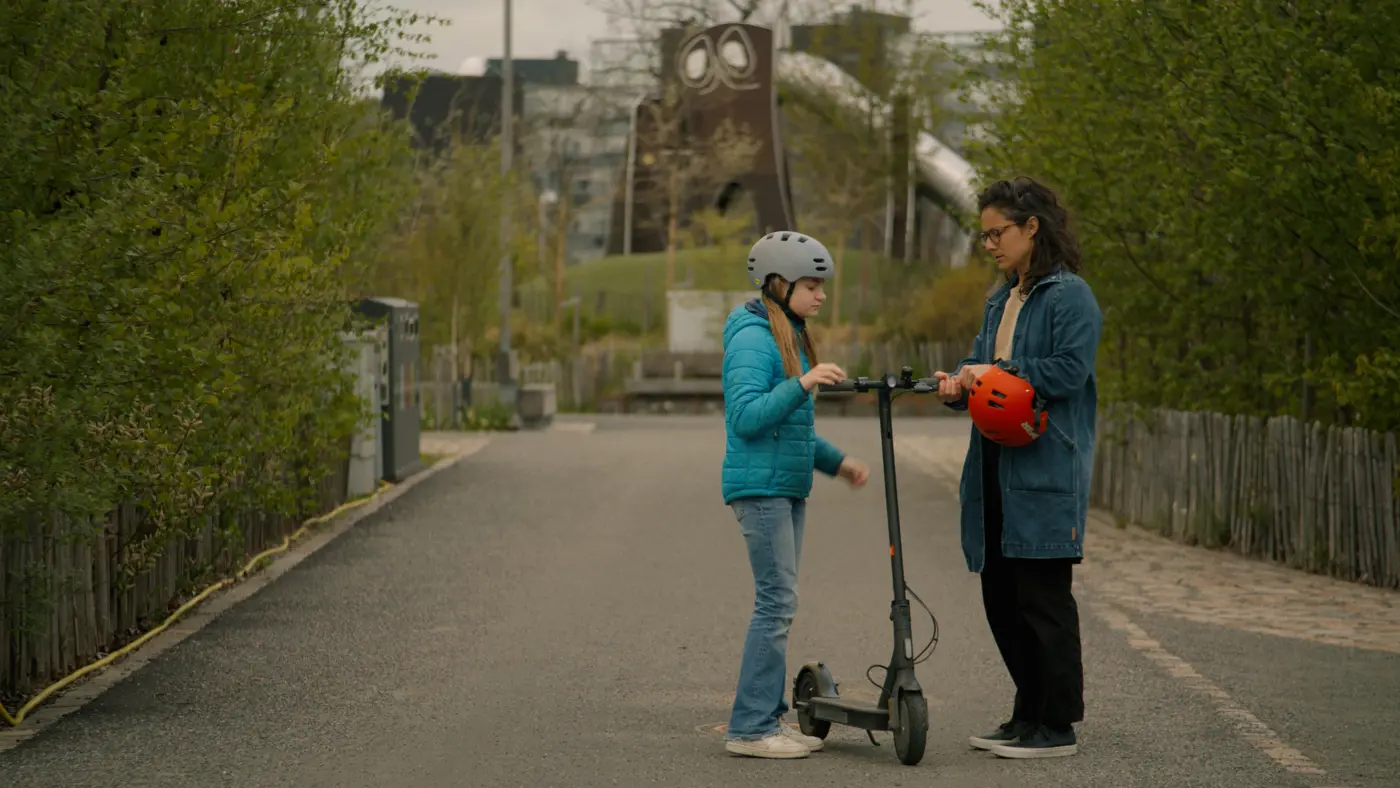 Ett barn och en förälder står med en elsparkcykel.