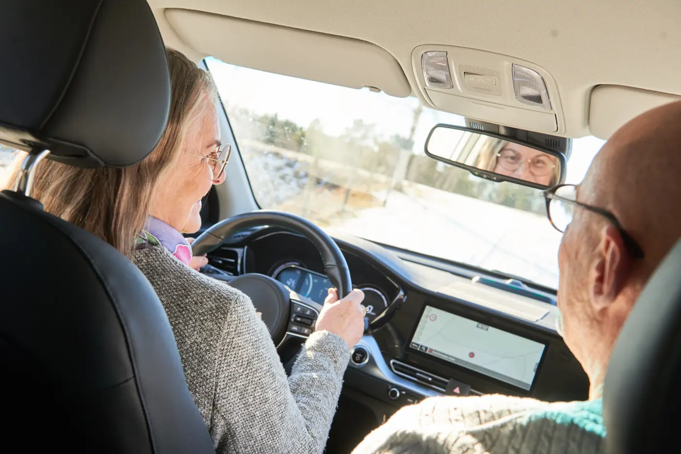 En äldre kvinna kör bil.