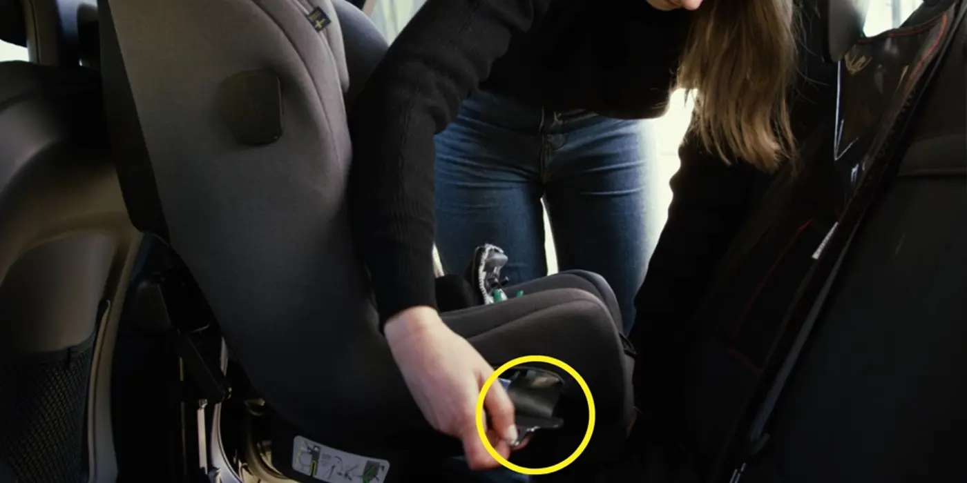 En förälder monterar en bakåtvänd bilbarnstol.