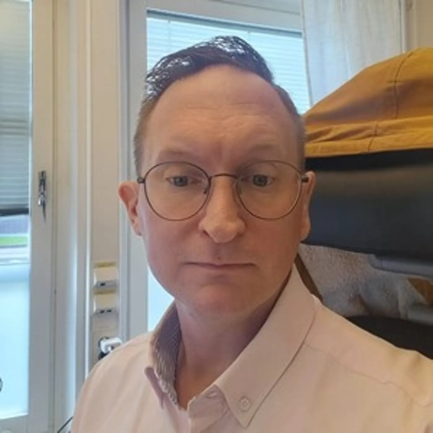 Porträttbild på en man med ljus skjorta och glasögon.