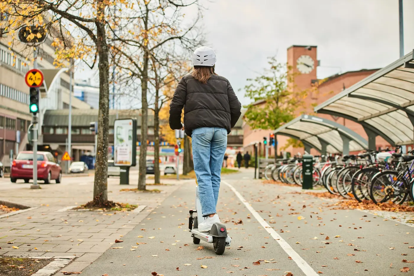 En tonåring med hjälm på huvudet kör elsparkcykel på en cykelbana.