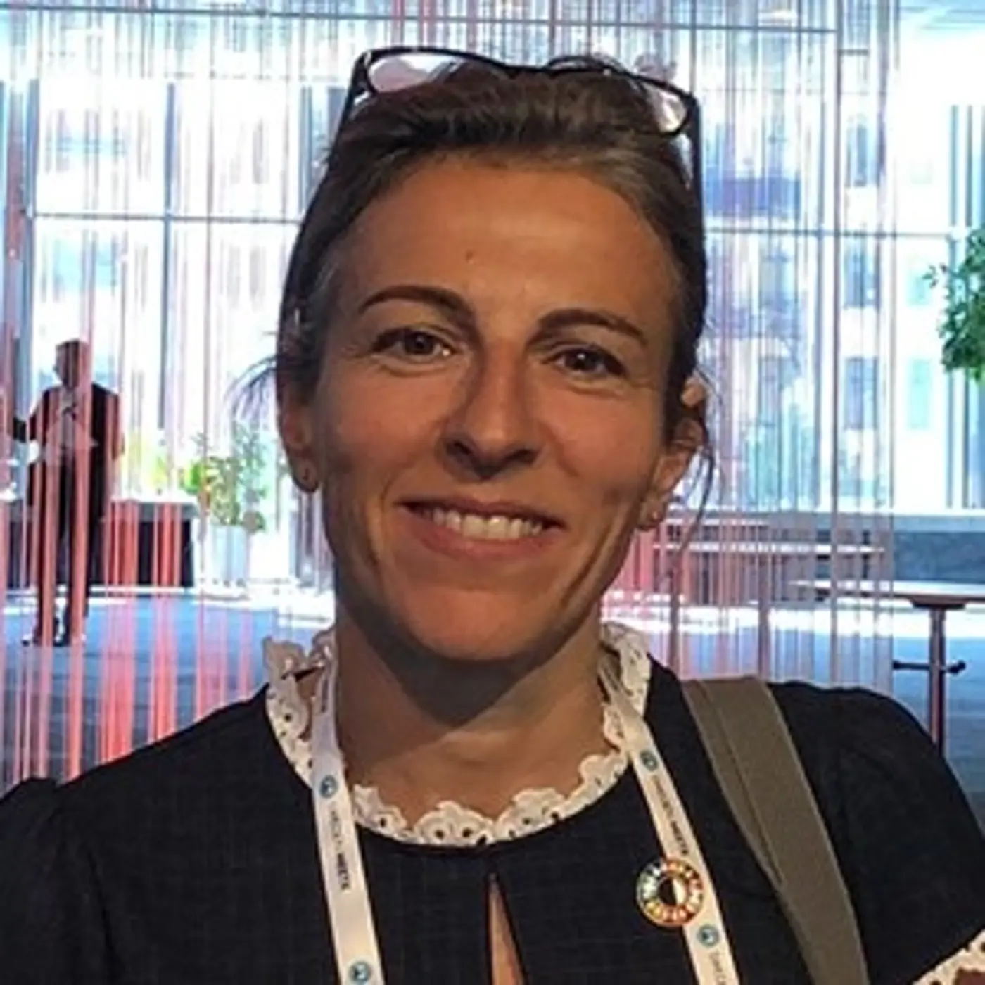 Porträttbild på en leende kvinna med uppsatt hår och glasögon på huvudet.