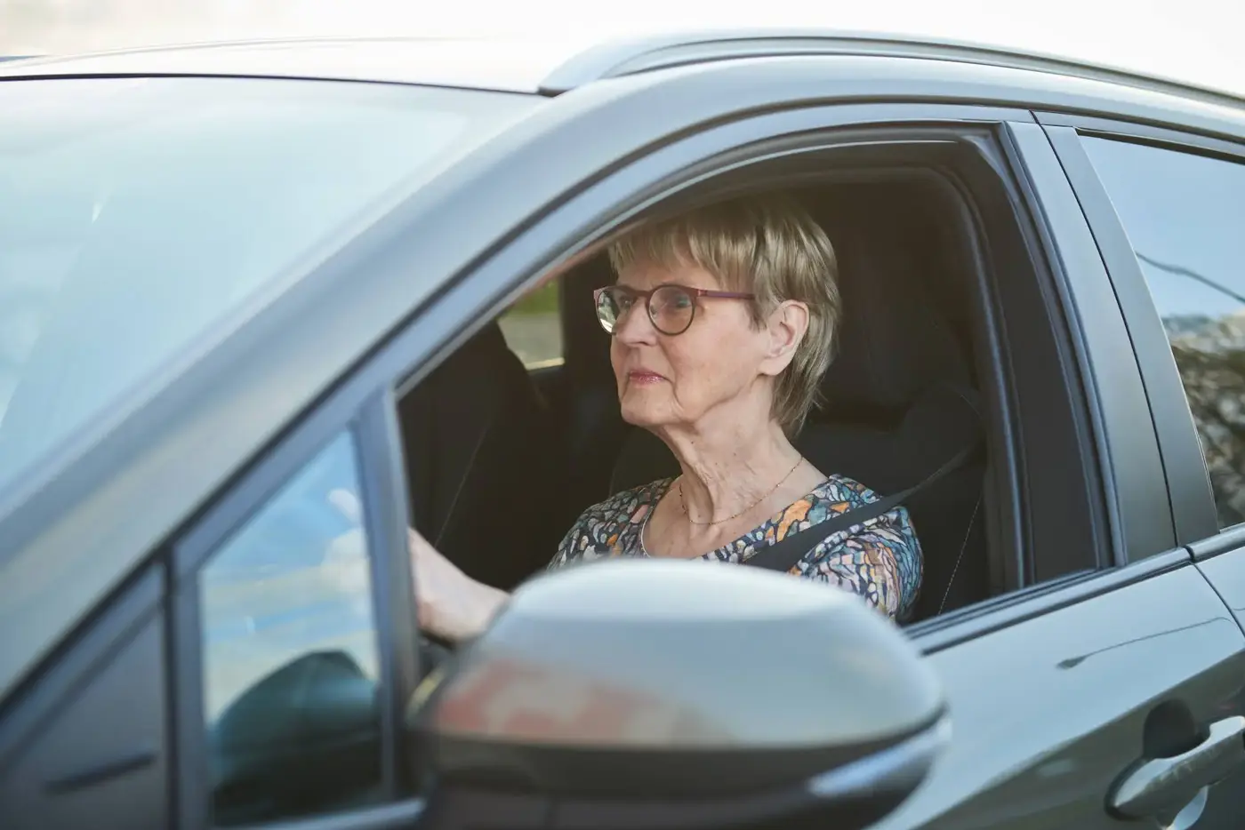 Äldre kvinna kör bil.