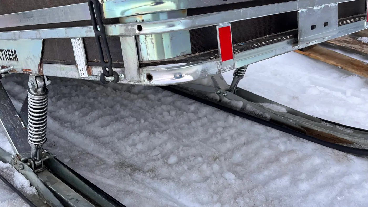 Närbild på ett skotersläp på snötäckt underlag.