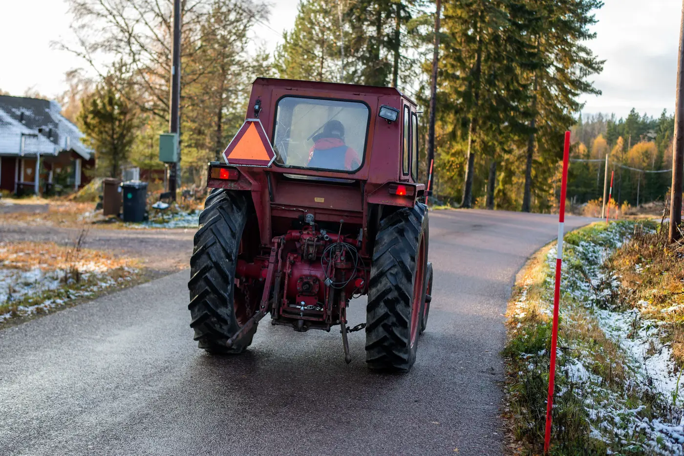 En traktor kör på en skogsväg. Bilden är tagen bakifrån.