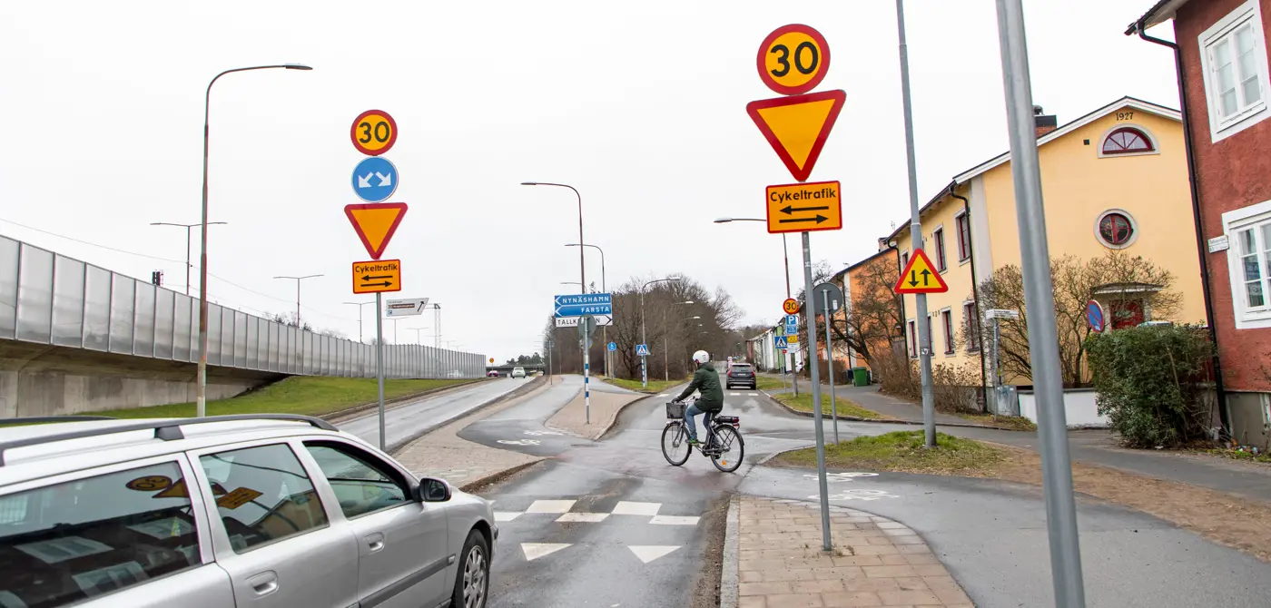 En man cyklar över en cykelpassage och framför står en bil och väntar på att få köra.