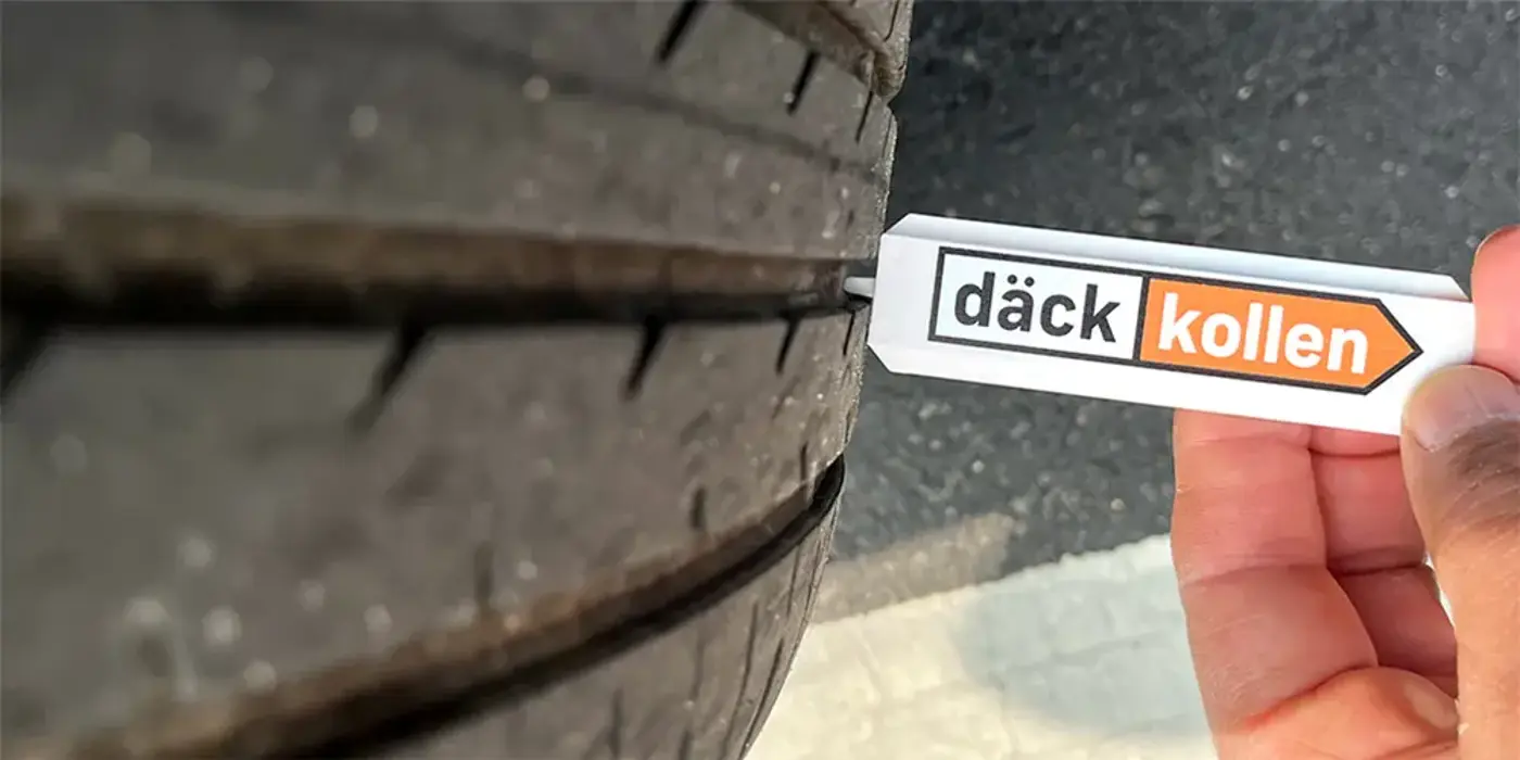 En hand håller i ett mätverktyg för att mäta mönsterdjup på ett bildäck.