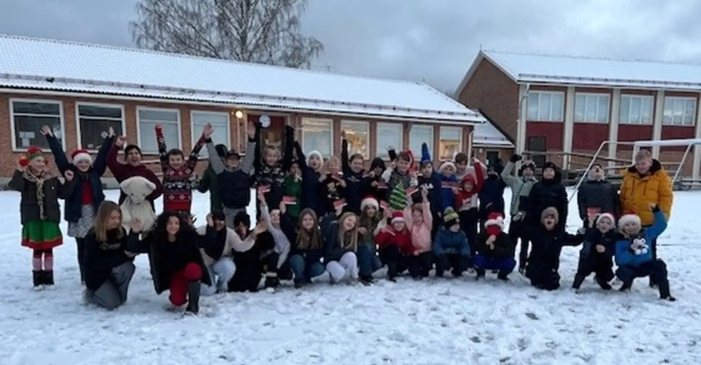 En skolklass står uppställda utanför en skola i vintermiljö.