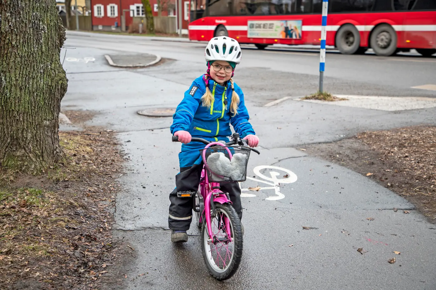 Ett barn kommer cyklandes på en cykelbana. I bakgrunden syns en buss köra förbi.