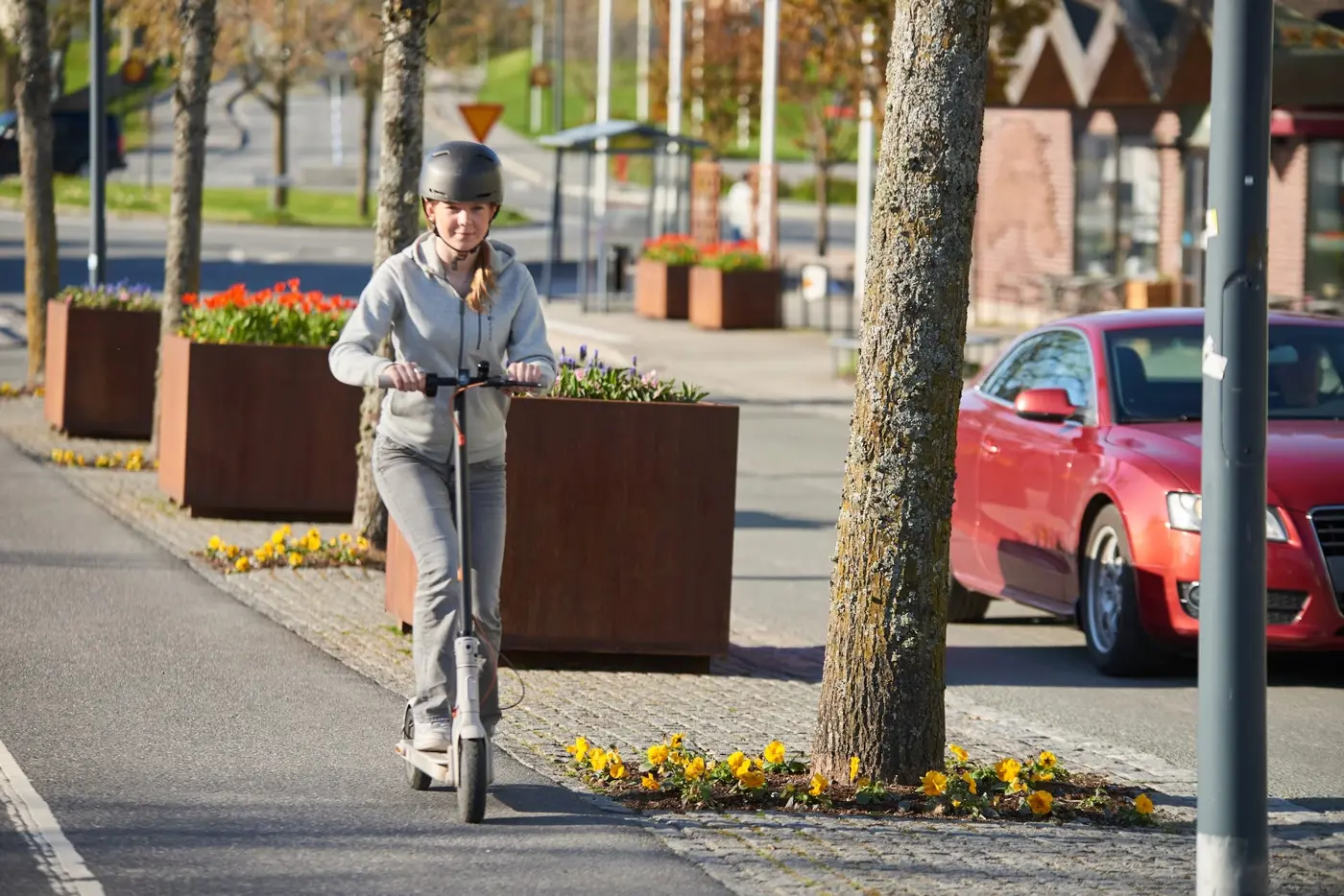En tonåring med hjälm på huvudet kör elsparkcykel på en cykelbana.
