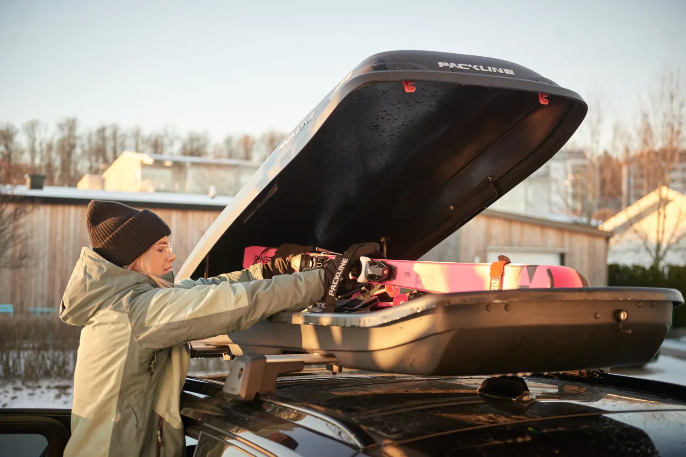 En kvinna packar in skidor i en takbox.