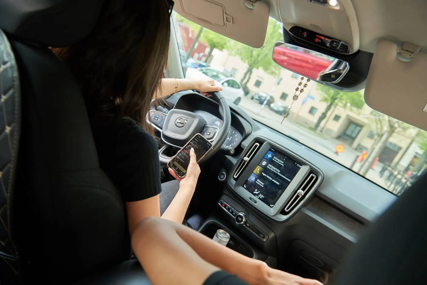 En ung förare kör bil samtidigt som hon använder telefonen. I framsätet sitter en även passagerare.