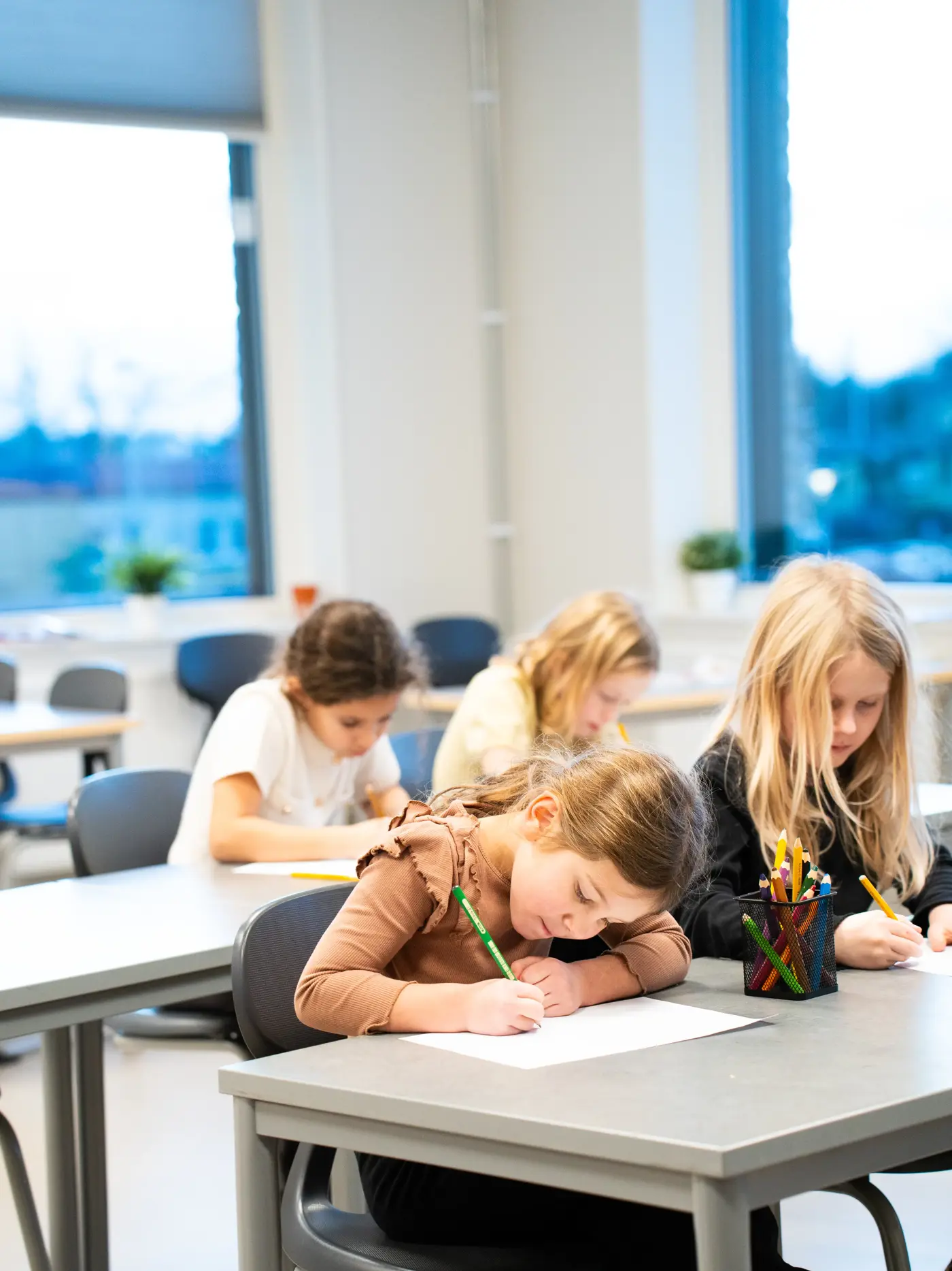 En grupp skolbarn sitter i sina bänkar och skriver.