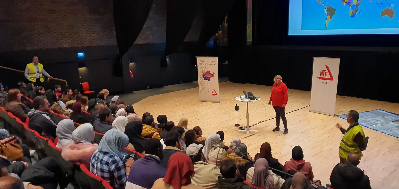 En kvinna föreläser framför en fullsatt föreläsningssal.