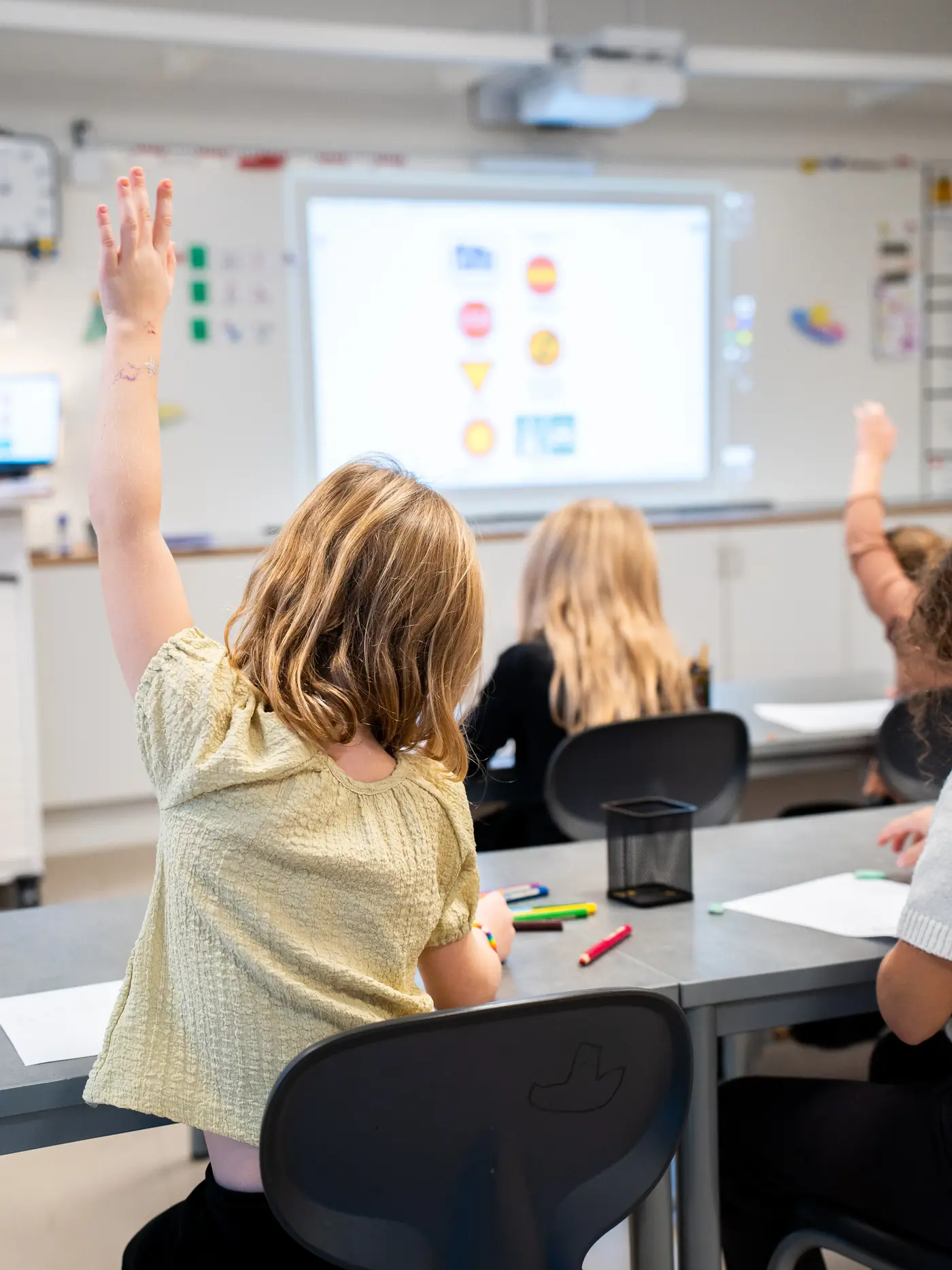 En grupp skolbarn sitter i sina bänkar och framför dem på tavlan visas en bild på olika vägmärken.