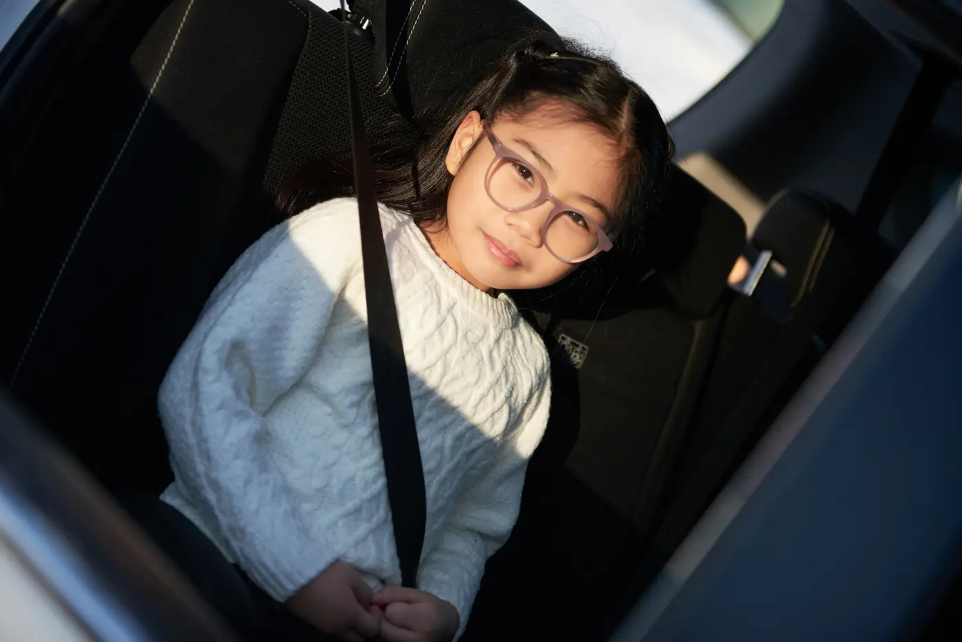 Ett barn sitter på en bälteskudde i passagerarsätet på en bil.