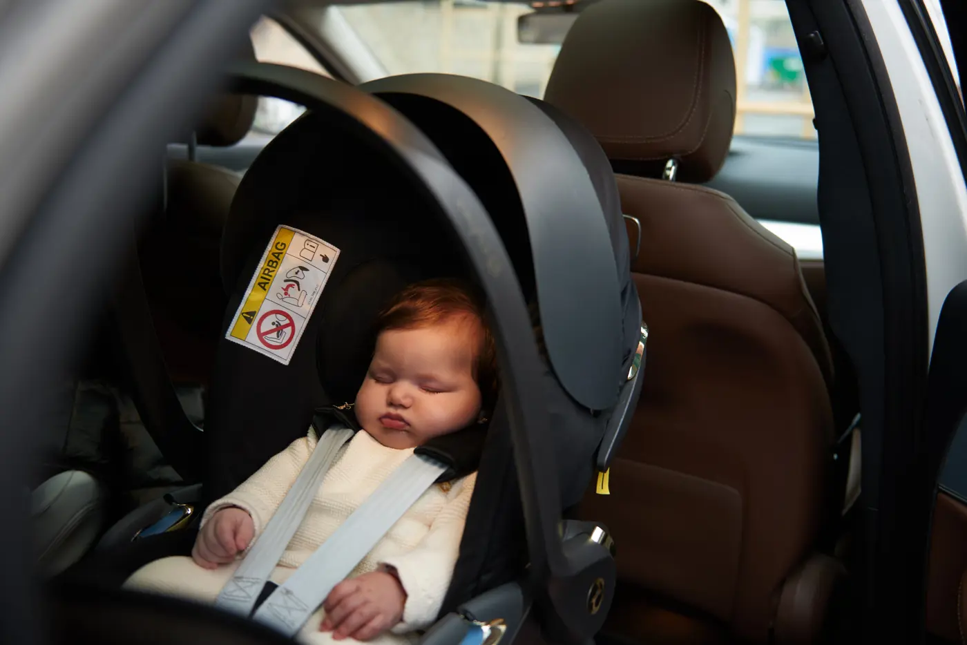 En bebis ligger och sover i ett babyskydd.