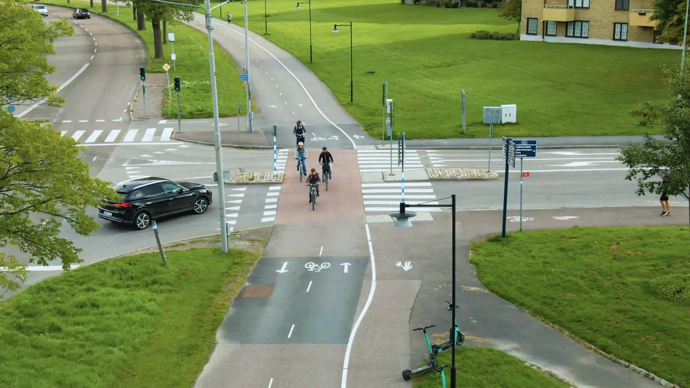 En drönarbild på en cykelöverfart och fyra barn som cyklar över medan en bil väntar på att få köra.