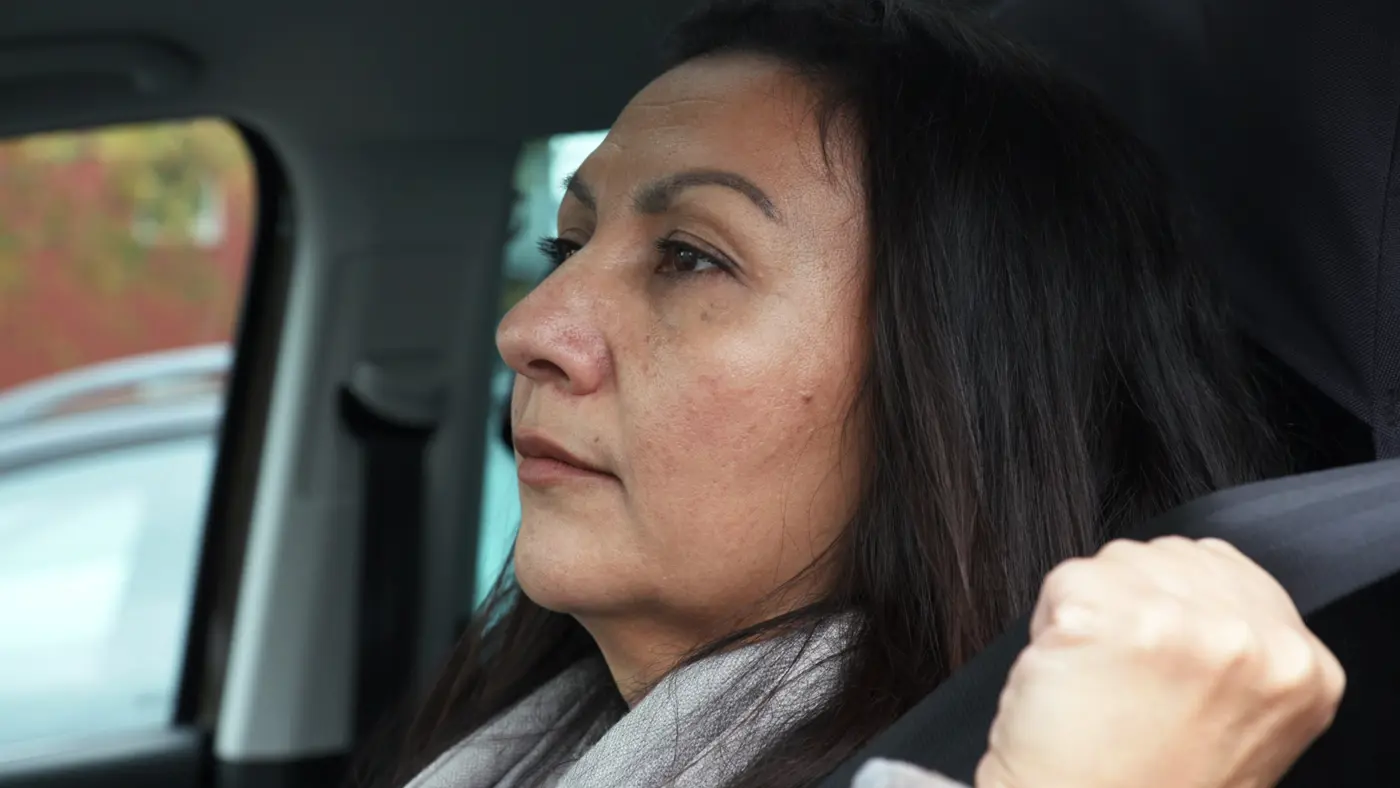 En kvinna sitter i en bil och håller på att spänna säkerhetsbältet