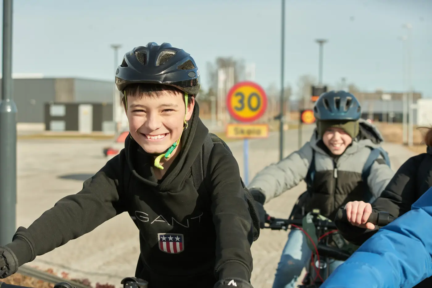Barn med cykelhjälm vid en hastighetsskylt för 30 kilometer i timmen
