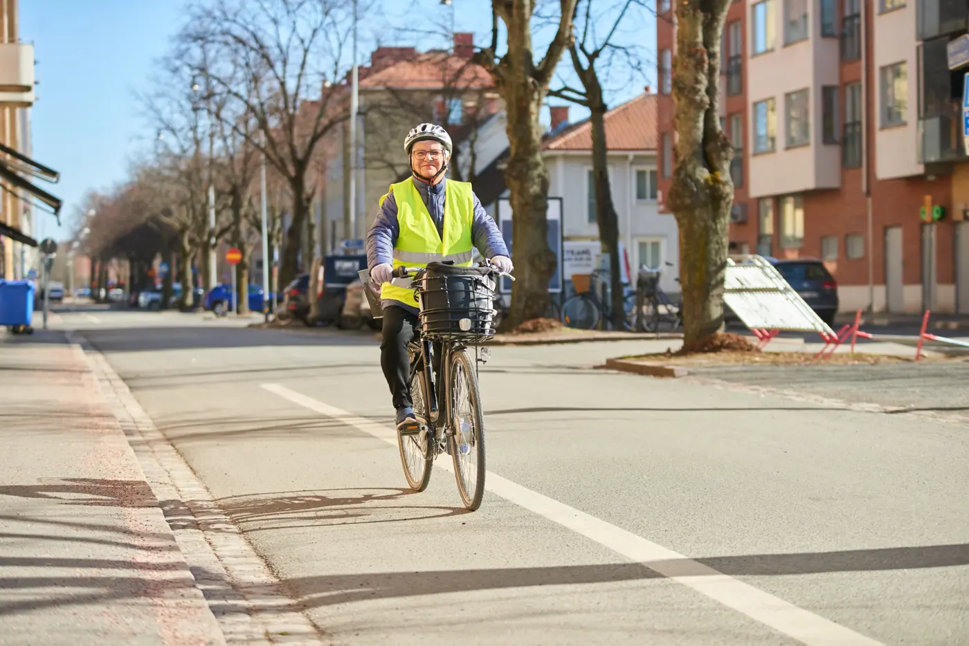 En äldre kvinna cyklar på en cykelbana i stadsmiljö