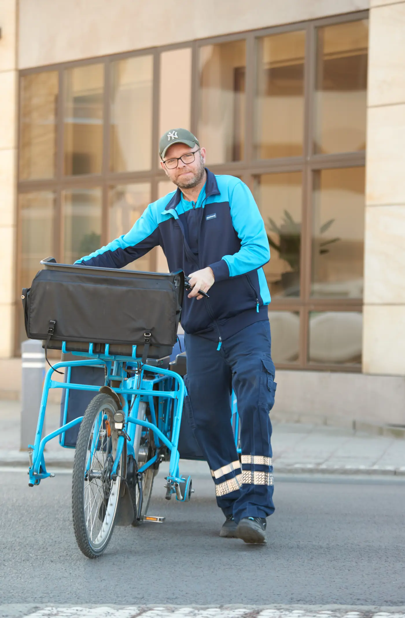En postutdelare leder sin cykel över en gata