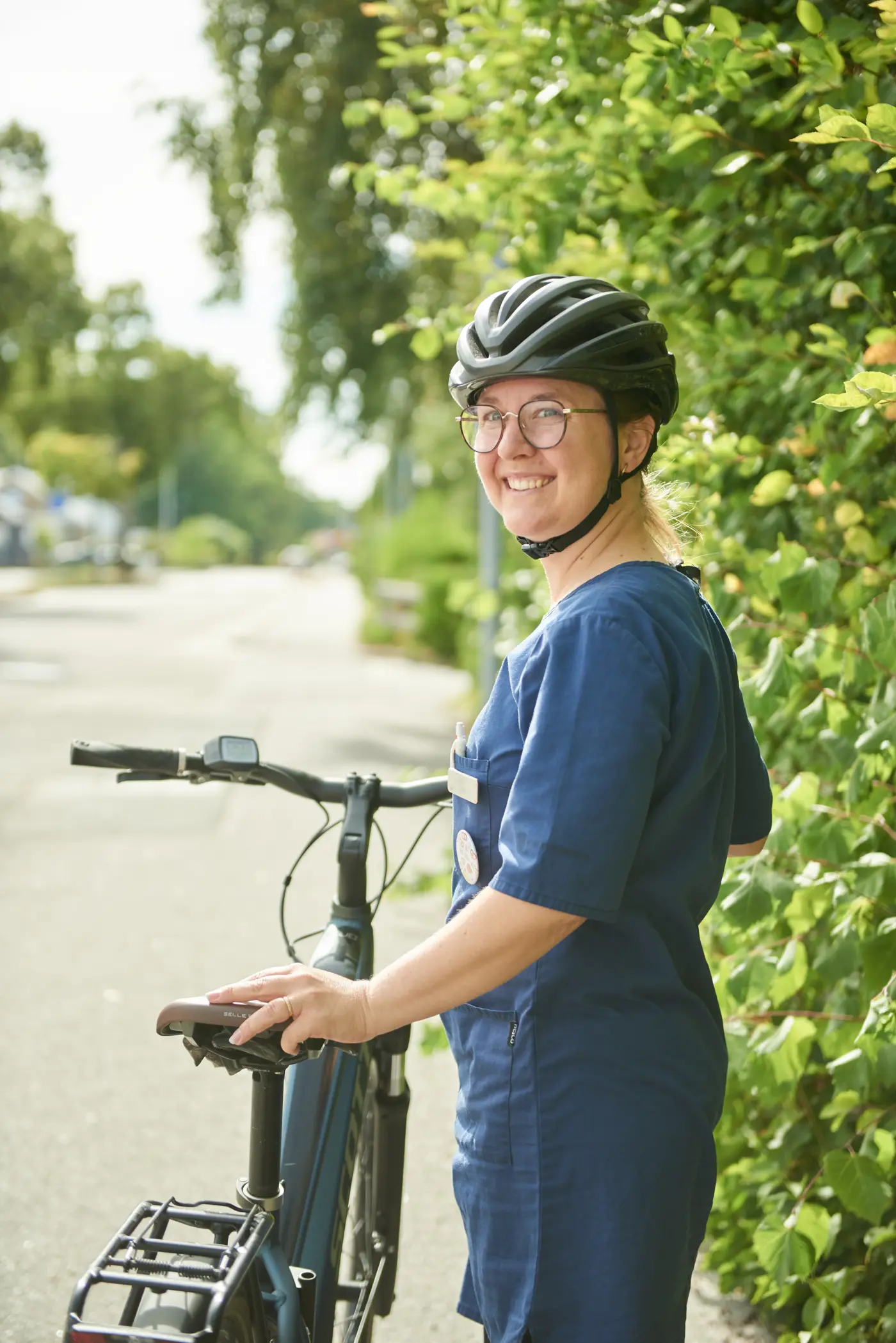En kvinnlig medarbetare inom hemtjänsten står med en cykel.