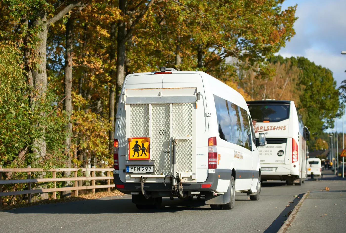 En mindre skolbuss kör bakom en större skolbuss.